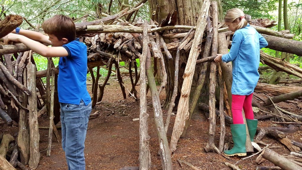 une fille et un garçon construisant une cabane en bois