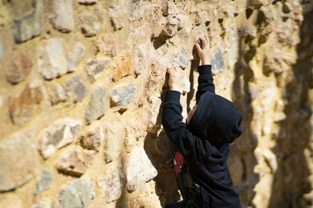 un enfant qui recommence d'escalader un mur après un échec