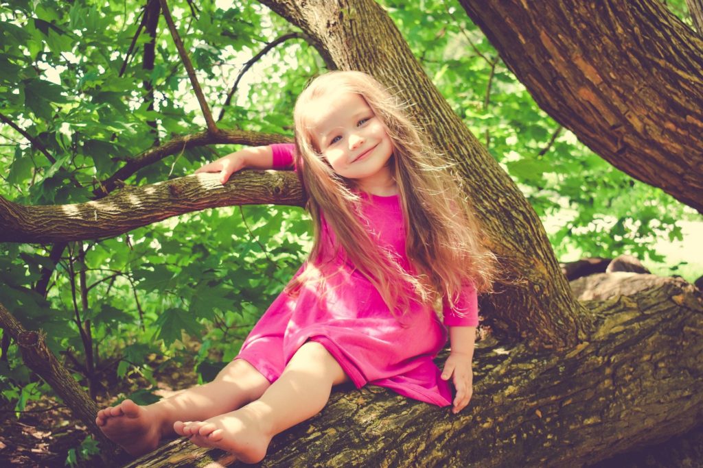 une enfant grimpant dans un arbre.